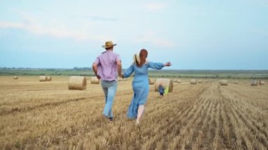 Evli çift, kağıt uçakla oğullarıyla el ele koşuyor.