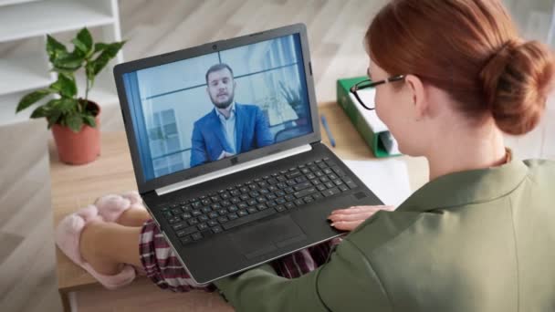 Mujer de negocios en pijama hablando con el ejecutivo masculino en el chat de vídeo remoto en la pantalla de la computadora mientras está sentado en el sofá en la oficina en casa durante la cuarentena — Vídeos de Stock