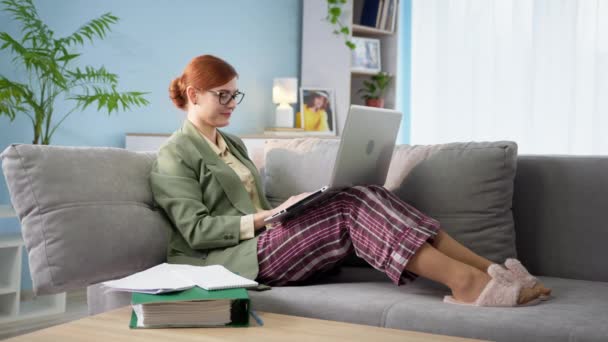 Businesswoman in jacket and pajamas is working remotely at home, talking on video call on laptop with colleague, remote work communication — Wideo stockowe