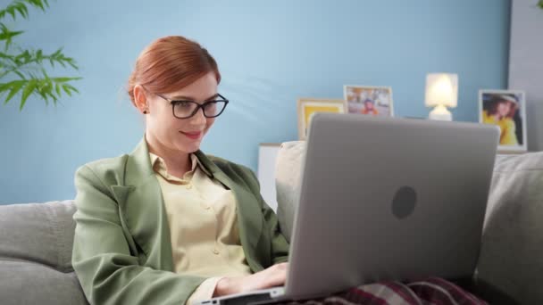 Mujer con chaqueta y pantalones de pijama trabajando en la computadora portátil en la oficina en el trabajo remoto — Vídeos de Stock