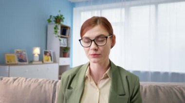 İş kadını, evinde, kanepede oturan bir müşteriyle bilgisayarla konuşuyor.