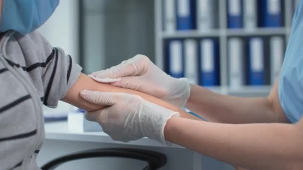 Világjárvány, közeli kéz az orvosi nővér biztonsági kesztyű csinál egy vakcina injekciót a kisfiú beteg egy egészségügyi klinikán — Stock videók