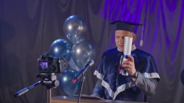 Diploma online, hoş üniversite öğretmeni mezunları konferans salonundaki kürsüde video bağlantısıyla tebrik ediyor.
