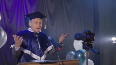 Yakışıklı adam üniversite öğretim üyesi akademik yılın sonunda konferans salonunda kamerasını kullanarak mezunları kutluyor.