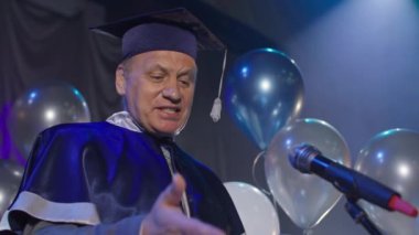 Uzaktan mezuniyet, neşeli öğretmen üniversite mezuniyetini akademik yılın sonunda kutluyor ve onlara konferans salonundaki başkanlık koltuğunda duran video bağlantısıyla internetten diplomalar veriyor.