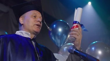 Mantodaki erkek öğretmen diploma töreni düzenliyor ve mezun olan öğrencileri sevinçle kutluyor.