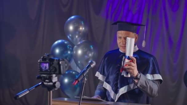 Diploma online, mooie universitaire leraar feliciteert afgestudeerden door videolink staan op stoel in conferentiezaal — Stockvideo