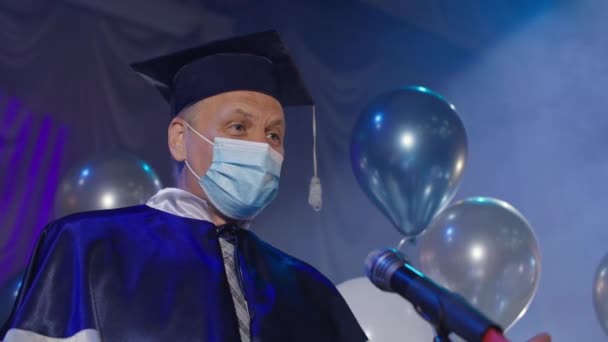 Docenti universitari in abito e maschera medica presentano solennemente diplomi ai laureati online durante la cerimonia di festa dei bambini in sala conferenze — Video Stock