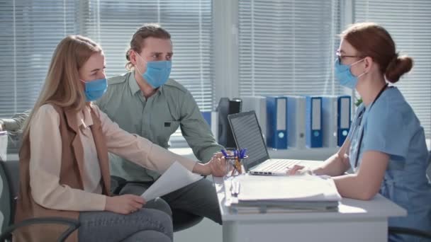 Medico professionista in maschera medica per proteggere contro virus e infezione consulta coppia sposata — Video Stock