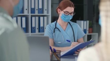 Üniformalı ve yüz maskeli doktor hastalara iyi haberler veriyor ve negatif kovid 19 testi, salgın hastalıklar gösteriyor.