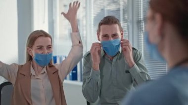 Evli çift mutlu bir şekilde tıbbi maskelerini çıkartıyor, kadın doktor neşeli aileye iyi haberler veriyor, covid-19