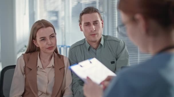 Gezondheid van het gezin, liefhebbende echtgenoot maakt zich zorgen over zijn vrouw slechte gezondheid en praat met arts tijdens medisch consult in het ziekenhuis — Stockvideo