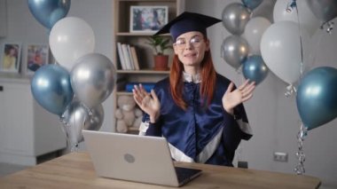 graduation ceremony online, charming graduate in academic dress rejoices at graduation from university during virtual graduation sitting at home