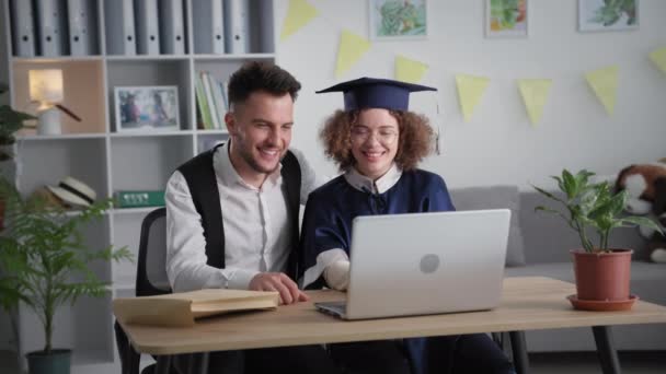 Aprendizagem moderna, jovem feliz e estudante do sexo feminino se alegrar e abraçar uns aos outros na cerimônia de formatura on-line via laptop link de vídeo regozijando graduação da faculdade — Vídeo de Stock