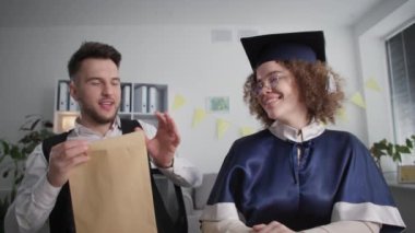 diploma online, young joyful student rejoices at received certificate of education together with smiling man during ceremony via video link on laptop