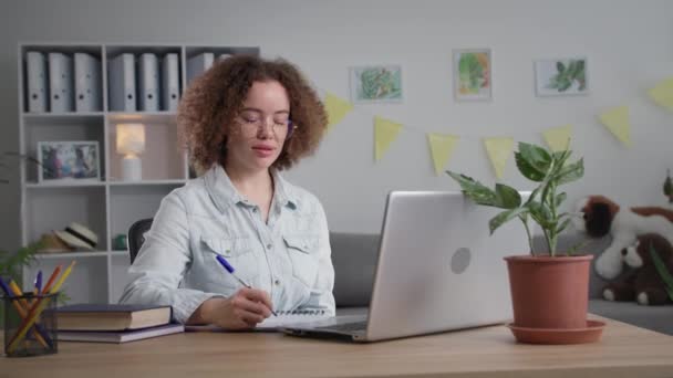 Remote education, beautiful young woman in glasses communicates with teacher via video call on laptop during an online training — Stock video