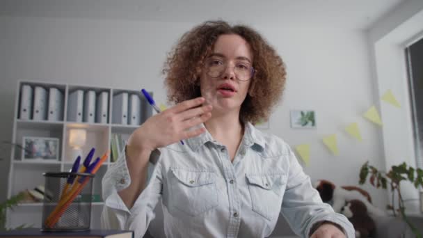 Онлайн-общение, симпатичная молодая женщина, проходящая дистанционное обучение посредством видеосвязи на ноутбуке поднимает руку и отвечает на вопросы — стоковое видео