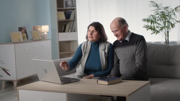 Loving elderly couple have fun together and browse online shopping on laptop — Stock video