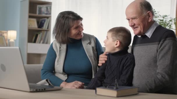 Riposo a casa, nonni premurosi insieme con bambino maschio carino, godere di guardare la TV sul computer portatile — Video Stock