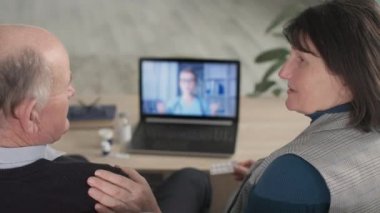 medical consultation, elderly family communicates about health and treatment with female doctor online via video call on laptop sitting at home