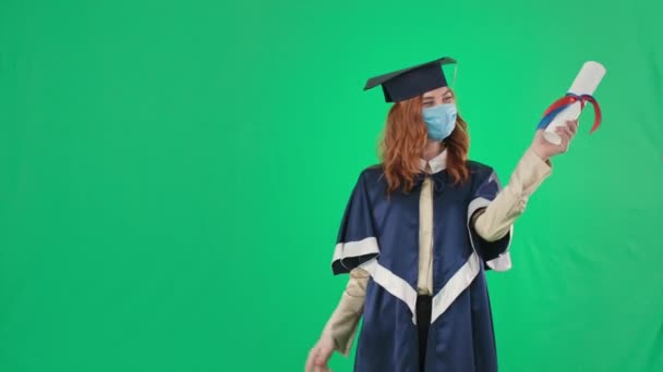 在检疫专业学习，戴着医疗面罩，手里拿着毕业证书，显示了她的大拇指背景，色彩斑斓的钥匙 — 图库视频影像