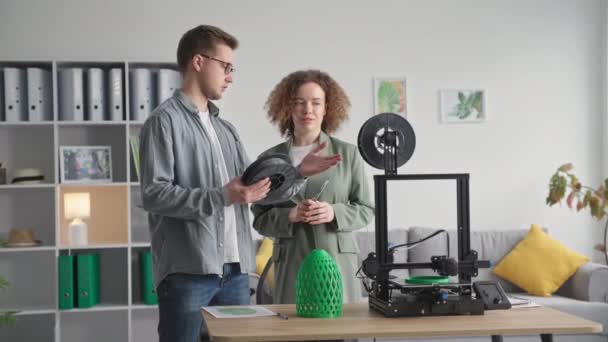 Moderne junge Designer Mann und Frau nutzen modernste Technologie lernt, wie man mit einem 3D-Drucker zu Hause arbeitet — Stockvideo