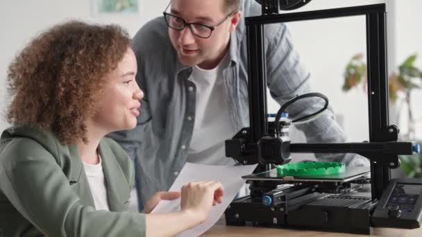 Charmante jonge vrouw met man kijken moderne huis model hd afdrukapparaat tijdens 3D-printer werk — Stockvideo