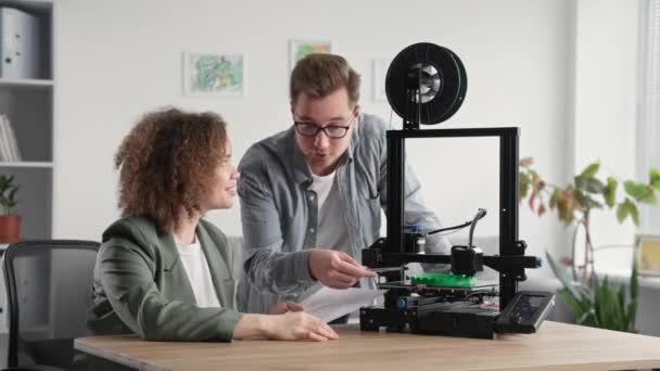 Jonge ingenieurs maken gebruik van moderne technologieën en observeren het proces van het printen van plastic producten op een 3D-printer thuis — Stockvideo