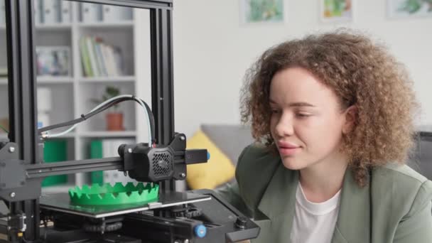 Portret van jonge mooie vrouwelijke ontwerper observeert moderne technologieën en kijkt naar werk afdrukken op 3D-printer — Stockvideo