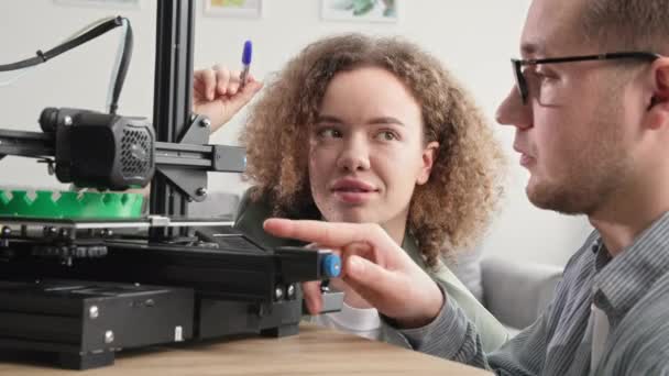 Giovani scienziati di sesso maschile e femminile osservano la creazione di un prototipo 3D complesso sulla stampante 3D a casa, tecnologia moderna — Video Stock