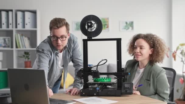 Modern erkek ve kadın ev ortamındaki 3D yazıcıya prototip ve baskı yapmak için dizüstü bilgisayar kullanıyor. — Stok video