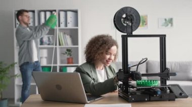 Genç yaratıcı erkek ve kadınların portreleri modern teknolojiyi kullanır ve evdeki 3D yazıcıda 3D bir abajur modeli basar.