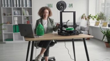 Tasarım ve mobilyalar, evdeki 3D yazıcıda bulunan ve gülümseyen ve kameraya bakan üç boyutlu lamba modelinin prototipi olan genç modern kız.