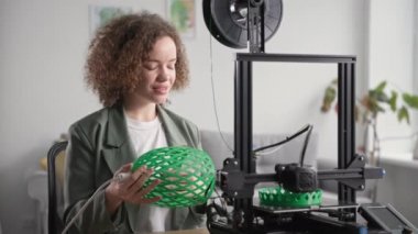 Modern teknolojiler, elinde lamba gölgesi olan yaratıcı kadın tasarımcı, oturma odasının geliştirilmesi için evdeki 3D yazıcıya basılmış, gülümseyen ve kameraya bakan