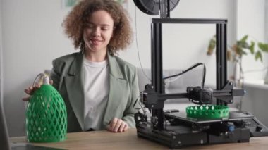 Lambanın prototipine sahip mutlu bir kadın. 3D yazıcıda el yapımı, modern teknolojileri kullanan, gülümseyen ve kameraya bakan.