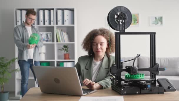 Innovatieve technologie, jonge creatieve jongen en meisje print een prototype van een lampenkap op een 3 d printer voor thuisgebruik in de woonkamer — Stockvideo