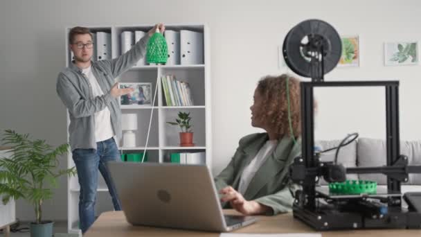 Nowoczesne technologie dla poprawy domu, młody mężczyzna i kobieta druk odcieni lampy na wydruku 3D w salonie — Wideo stockowe