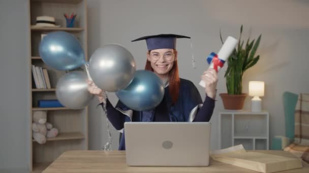 Modernes Lernen, glückliche Studentin in Mantel und Hut freut sich über Hochschuldiplom mit Luftballons in den Händen — Stockvideo