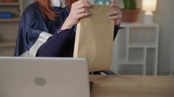 Distance learning, adult female graduate in academic clothes rejoices diploma online, takes out certificate from an envelope — Stock Video