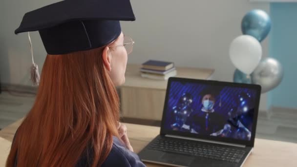 Laurea online, giovane donna in abito accademico orologi cerimonia di laurea online comunica con un insegnante di università maschile — Video Stock