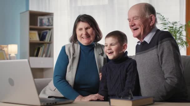 Infanzia, adorabile bambino maschio insieme ai nonni, si gode il proprio riposo a guardare il programma di intrattenimento sul computer portatile — Video Stock