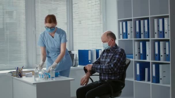안면 마스크를 쓰고 있는 여성 의료 종사자 가 병원 병실에 있는 나이든 남성 환자에게 주사기로 바이러스를 주사하고 감염 약물을 투여하는 모습 — 비디오