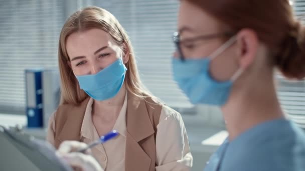 Kadın doktor resepsiyonunda maske takan kadın muayene oluyor. — Stok video
