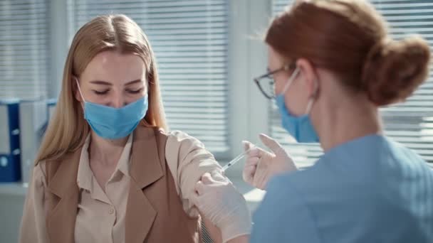 Enfermeira usando luvas de proteção usa seringa para injetar a vacina do vírus para tratar paciente do sexo feminino — Vídeo de Stock