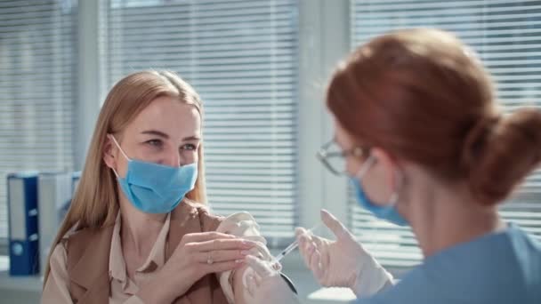 医師事務所におけるウイルスや感染の予防や治療のためにワクチンを注射する保護マスクの幸せな女性患者 — ストック動画