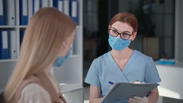 Medico donna in maschera medica e guanti per proteggere contro il virus misura la temperatura dei pazienti con termometro senza contatto — Video Stock