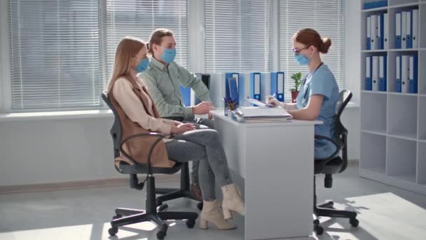 Couple wearing medical masks to protect against virus in doctor office undergo medical examinations — Stock Video