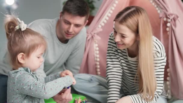 Barnens motorik, bedårande kvinnligt barn leker med mamma och pappa under familjen kul med wigwam hemma — Stockvideo