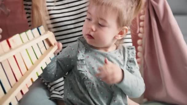 Porträt eines gesunden zufriedenen weiblichen Kindes, das mit Spielzeug spielt, zusammen mit einer fürsorglichen Mutter zu Hause, Nahaufnahme — Stockvideo
