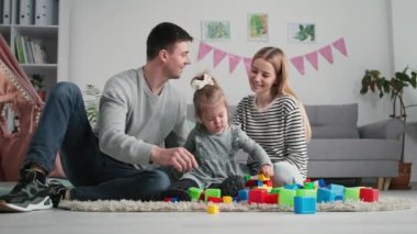 Aile ilişkileri, neşeli ebeveynler ve küçük bayan çocuk, yerde duran renkli plastik bilgisayarla eğitici oyunlar oynayarak tatilin tadını çıkarın.